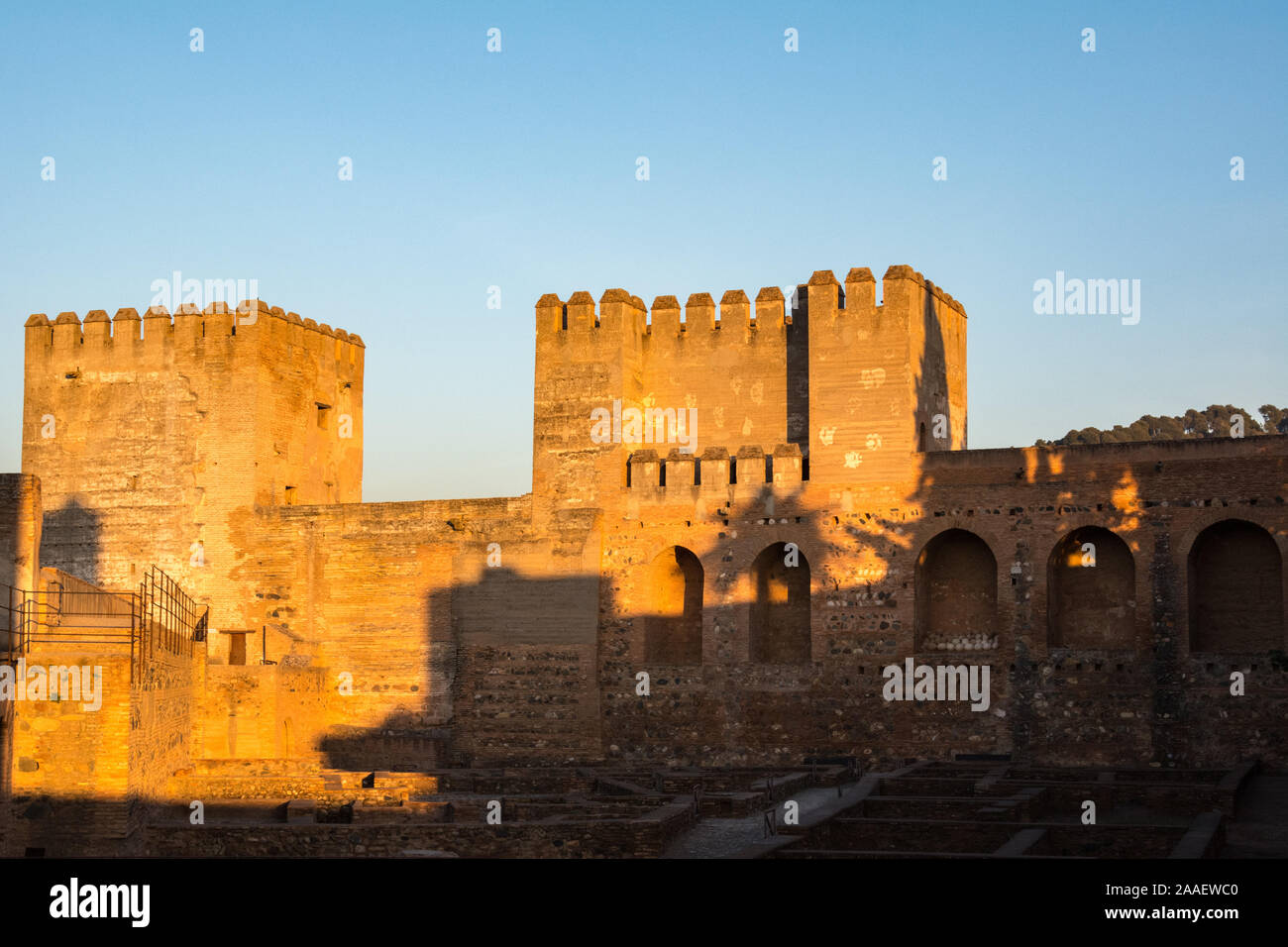 Turrets of the Alcazaba, the fortress of the Alhambra palace complex photographed in the golden hour. A portion of Arms Square is visible. Stock Photo