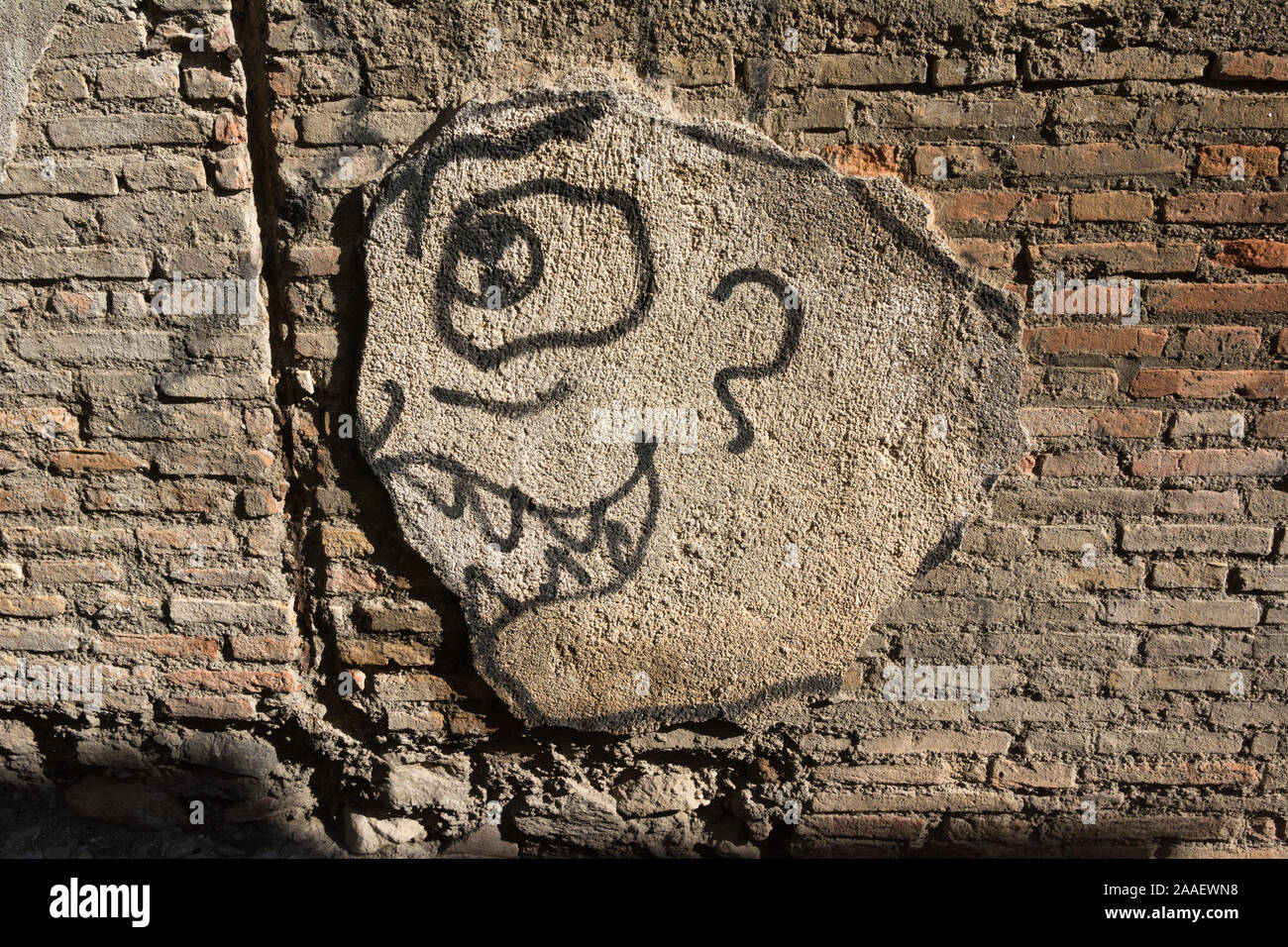 A funny face drawn onto a lump of plaster on an old brick wall Stock Photo
