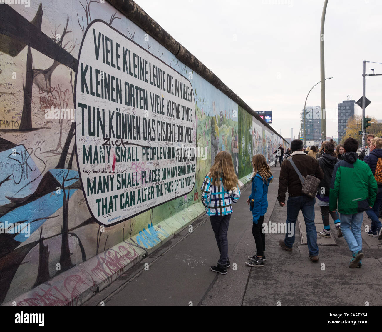 Visitors to the East Side Gallery in Berlin admire a mural with words painted in German and English on a remnant of the Berlin Wall Stock Photo