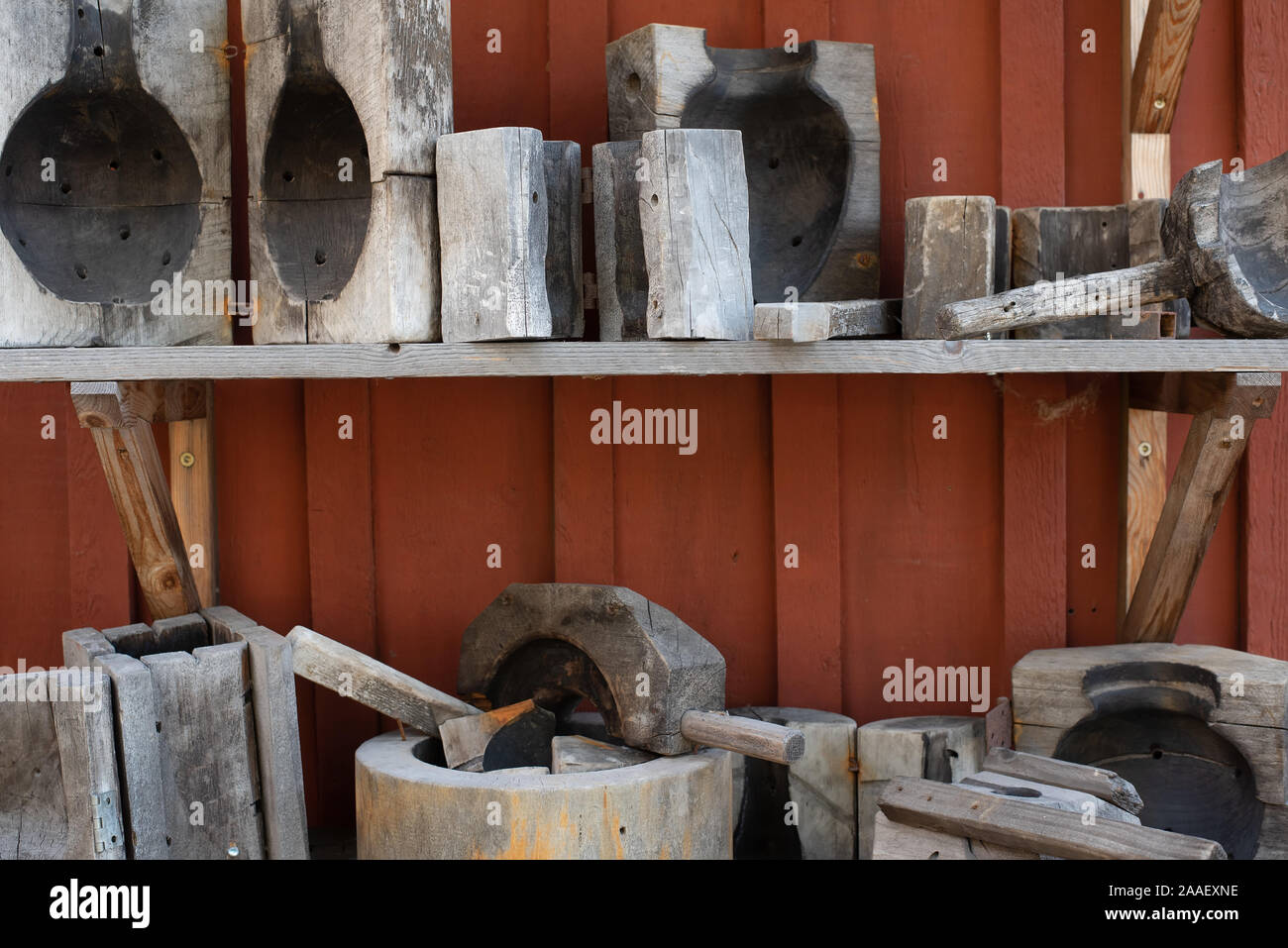 Old tools and forms for glass blowering on a shelf on a red rustic wooden wall Stock Photo