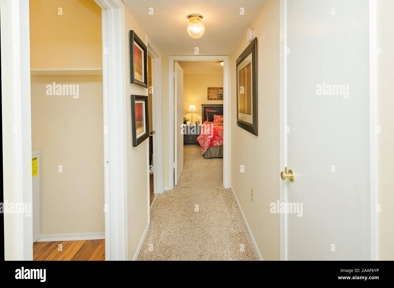 A narrow hallway features framed art at Four Seasons apartments in Mobile, Alabama. The apartment complex is owned and operated by Sealy Management. Stock Photo