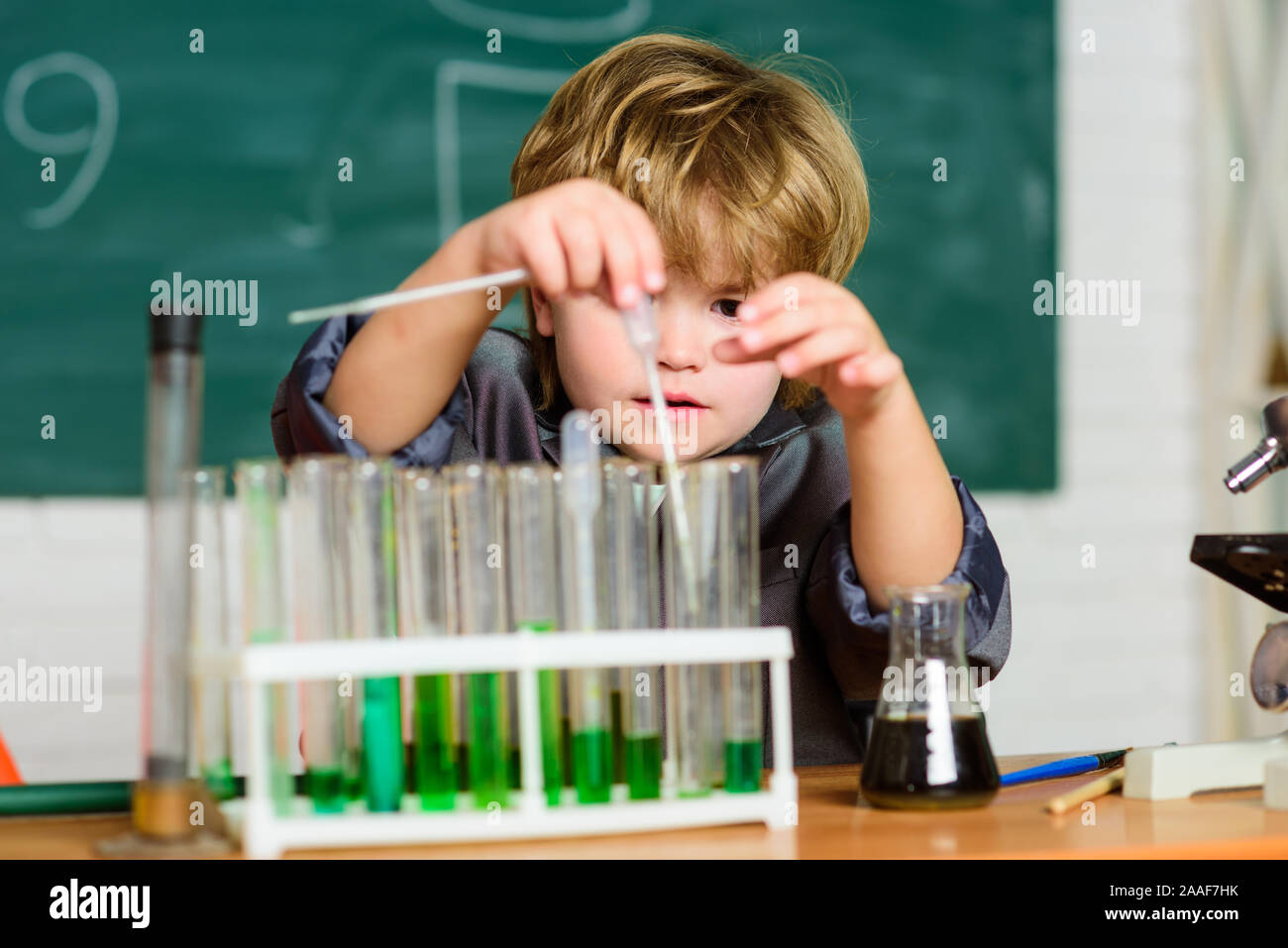 Little kid learning chemistry in school laboratory. experimenting with ...