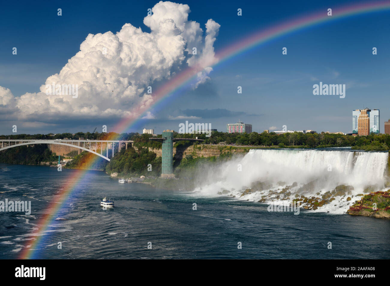 Rainbow Bridge and Niagara Falls Observation Tower with cumulus cloud and rainbow over US Falls on the Niagara river Stock Photo