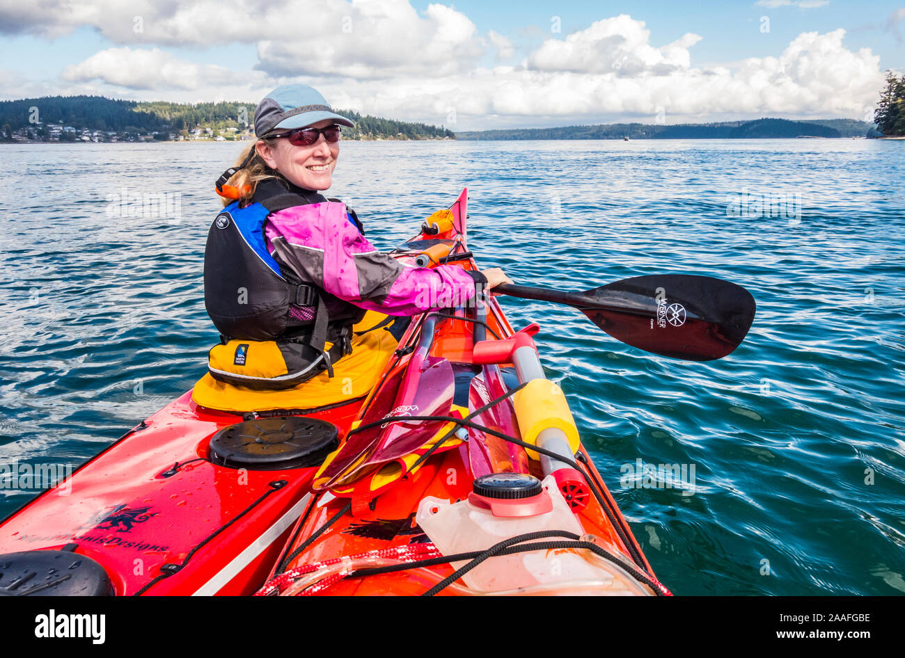 A female sea kayaker rafted up with another kayak posing for a picture