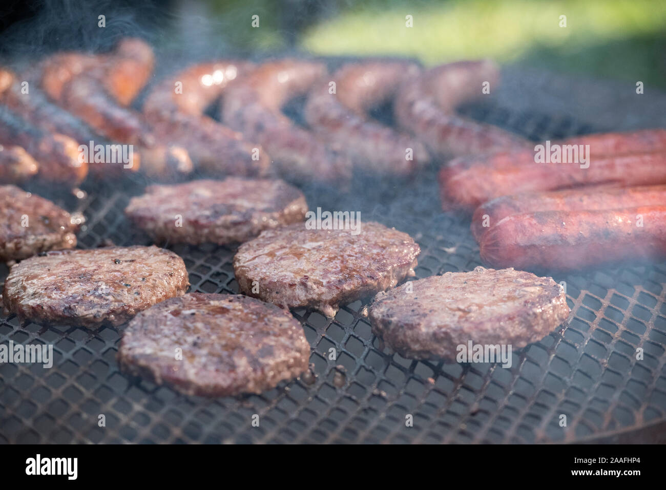 Hamburger patties, sausages, and hot dog wieners being cooked over an