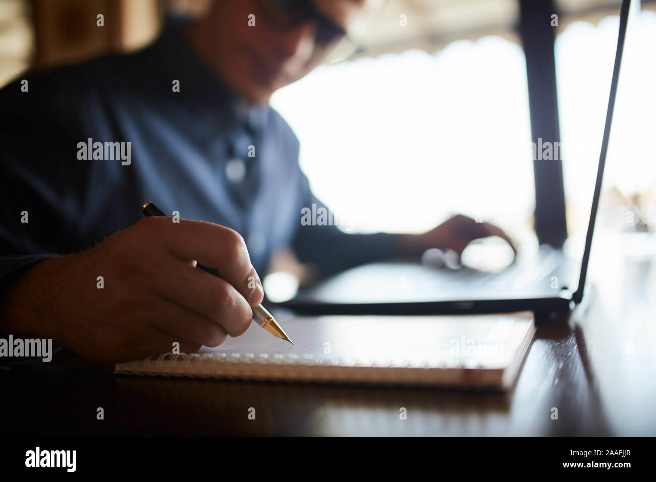 Close-up of man hand writing on paper notebook. Young businessman in ...