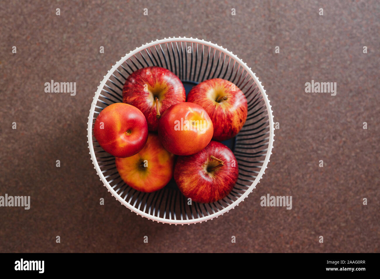 Basket With Red Apples And Nectarine On Kitchen Benchtop Topdown