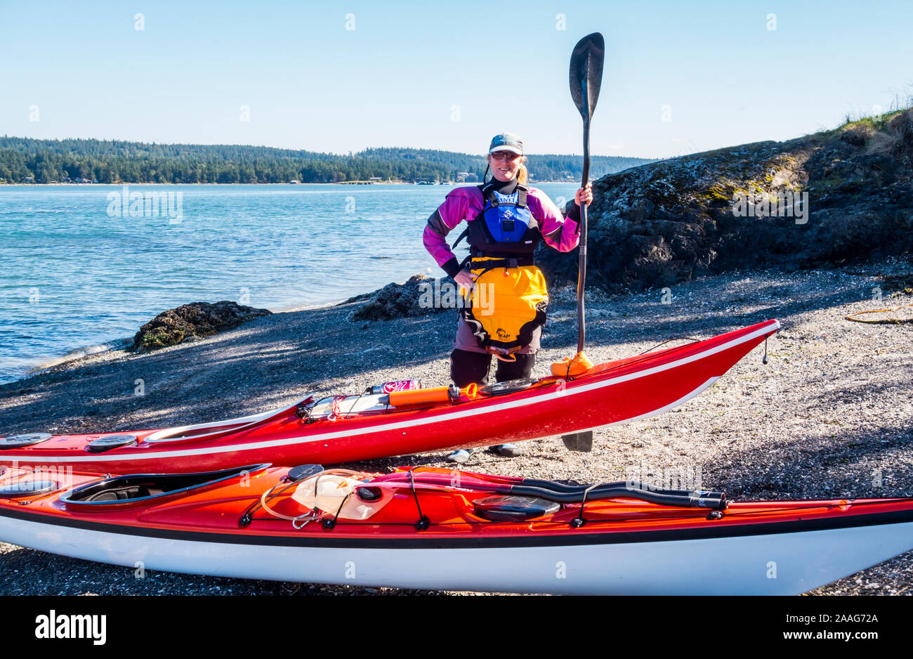 A woman poses for a picture with her sea kayak on Skagit Island, Washington in Skagit Bay, Washington, USA. Stock Photo