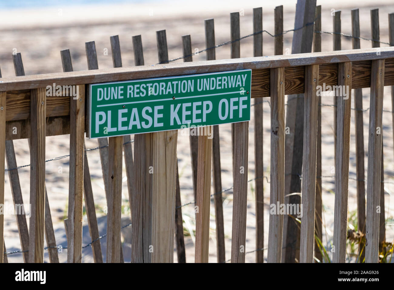 Green sign at beach reads: 'DUNE RESTORATION UNDERWAY - PLEASE KEEP OFF' Stock Photo