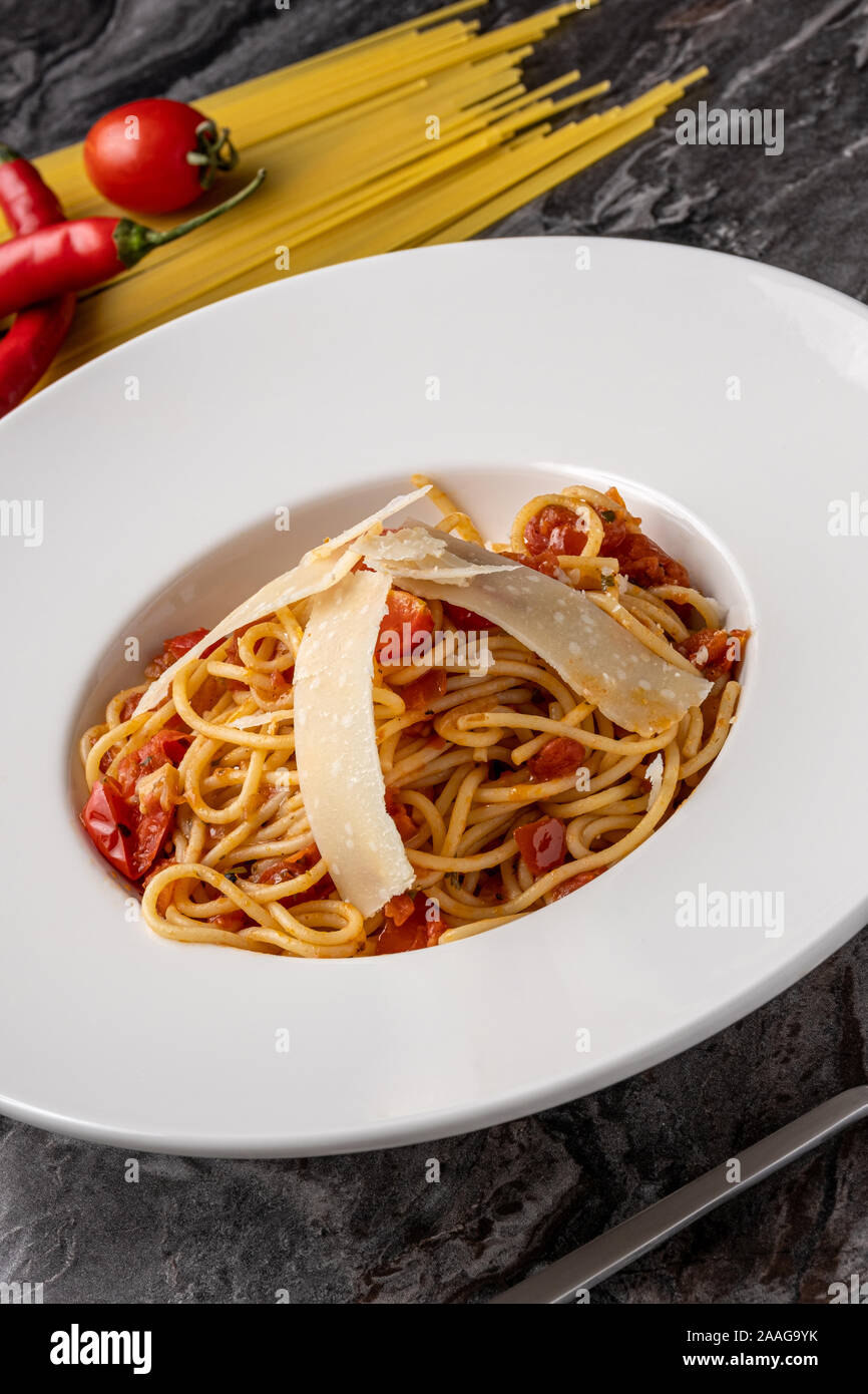 Spaghetti with a spicy sauce, chili pepper and grated parmesan cheese