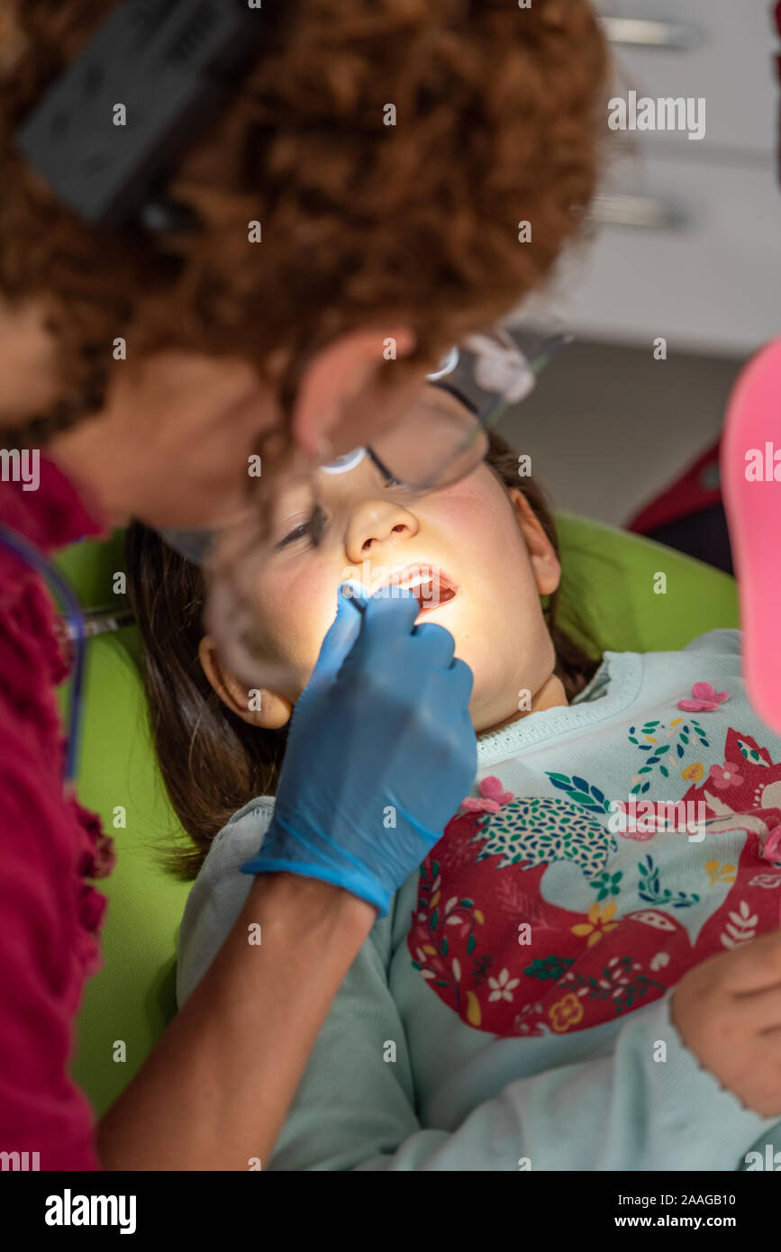 Dentist examining young girl in dental clinic Stock Photo