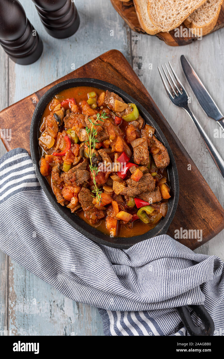 Beef stew with potatoes, carrots and herbs in iron casserole, top view Stock Photo