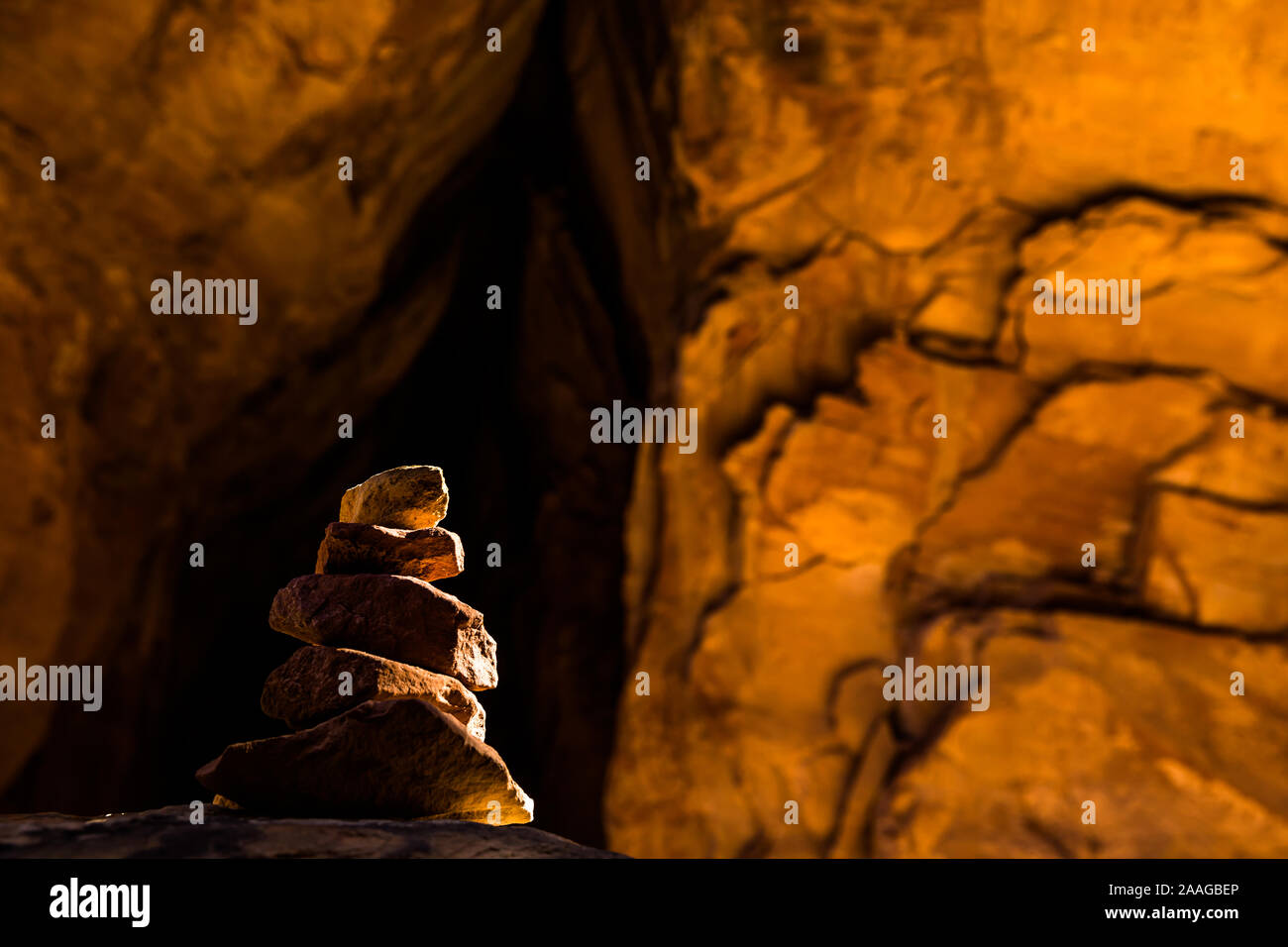 Cairn in dark tunnel through red sandstone slickrock in Moab Utah. Near Arches, Canyonlands, Bryce, Zion, Capital Reef National Parks. Stock Photo