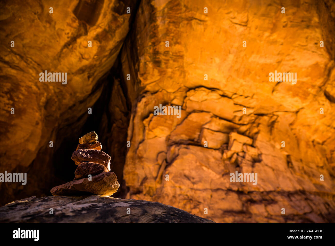 Cairn in narrow canyon with textured sandstone walls of bright orange rock near Moab Utah. Joint Trail through Canyonlands National Park. Stock Photo