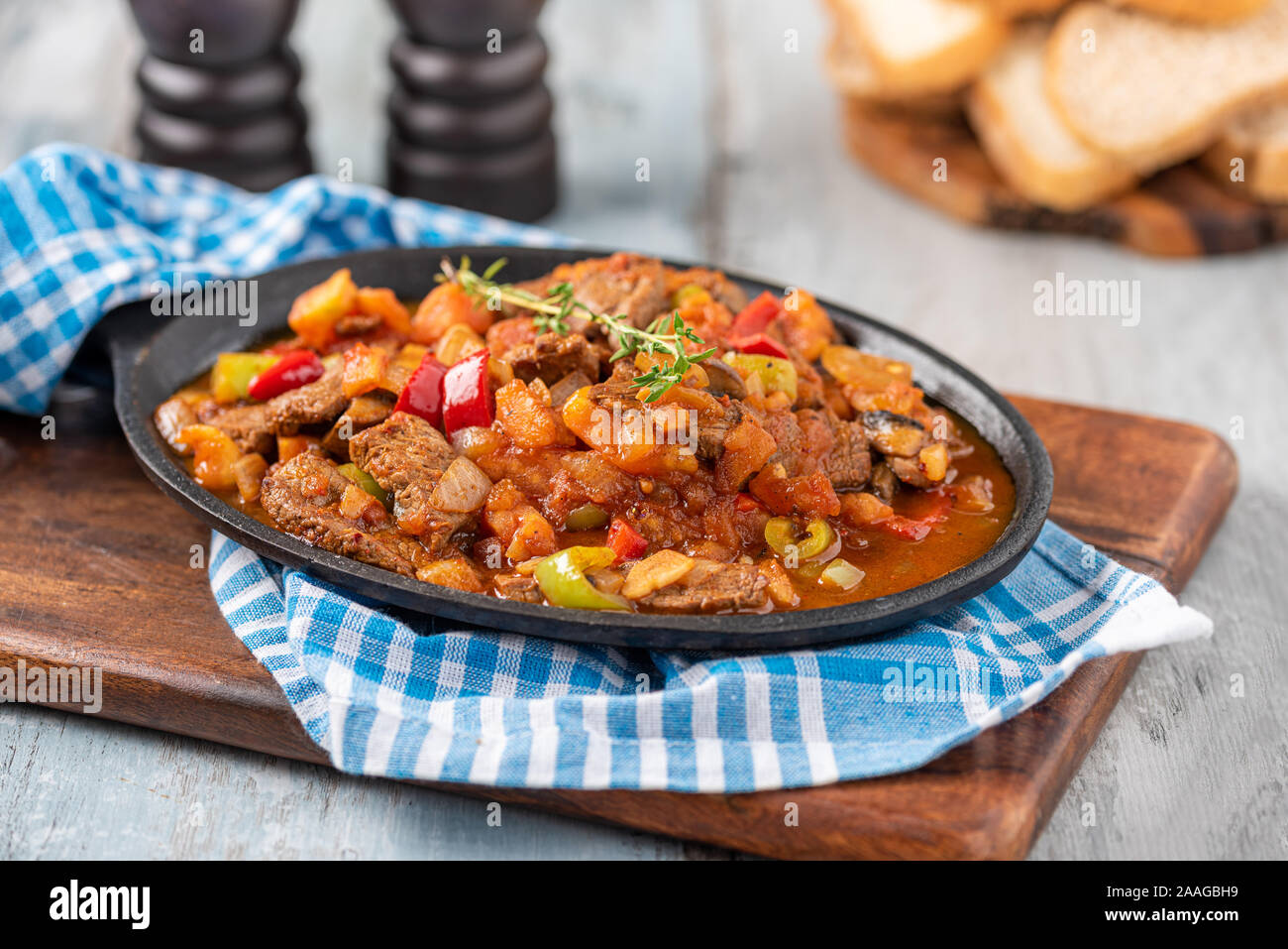 Beef stew with potatoes, carrots and herbs in iron casserole, top view Stock Photo