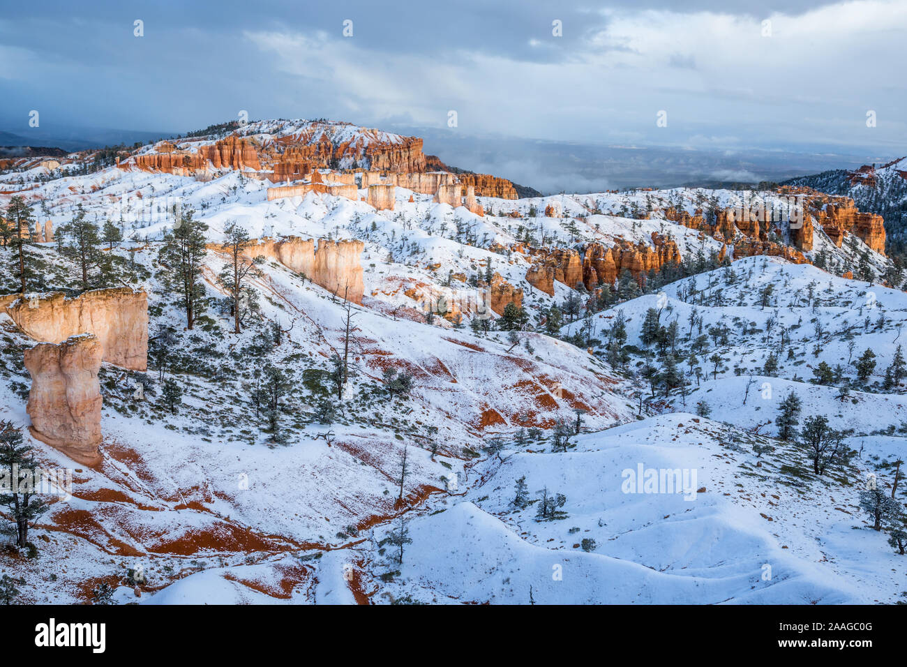 Evening light breaks through winter storm clouds after snow falls in southern Utah's Bryce Canyon National Park. Stock Photo