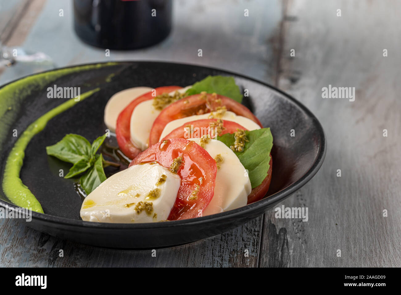 Fresh italian caprese salad with mozzarella and tomatoes on dark plate Stock Photo