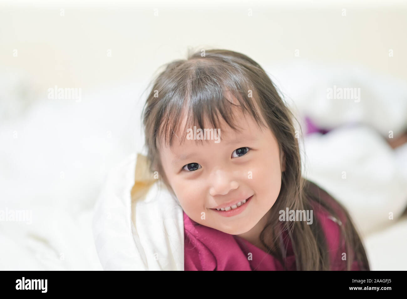 Asian little girl Wake up with a bright smile on the bed on the morning time with sunrise light soft focus sweet dream concept Stock Photo