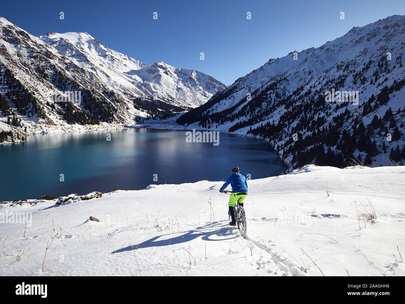 Cyclist rides at snow Shore of Mountain Lake in Almaty, Kazakhstan Stock Photo