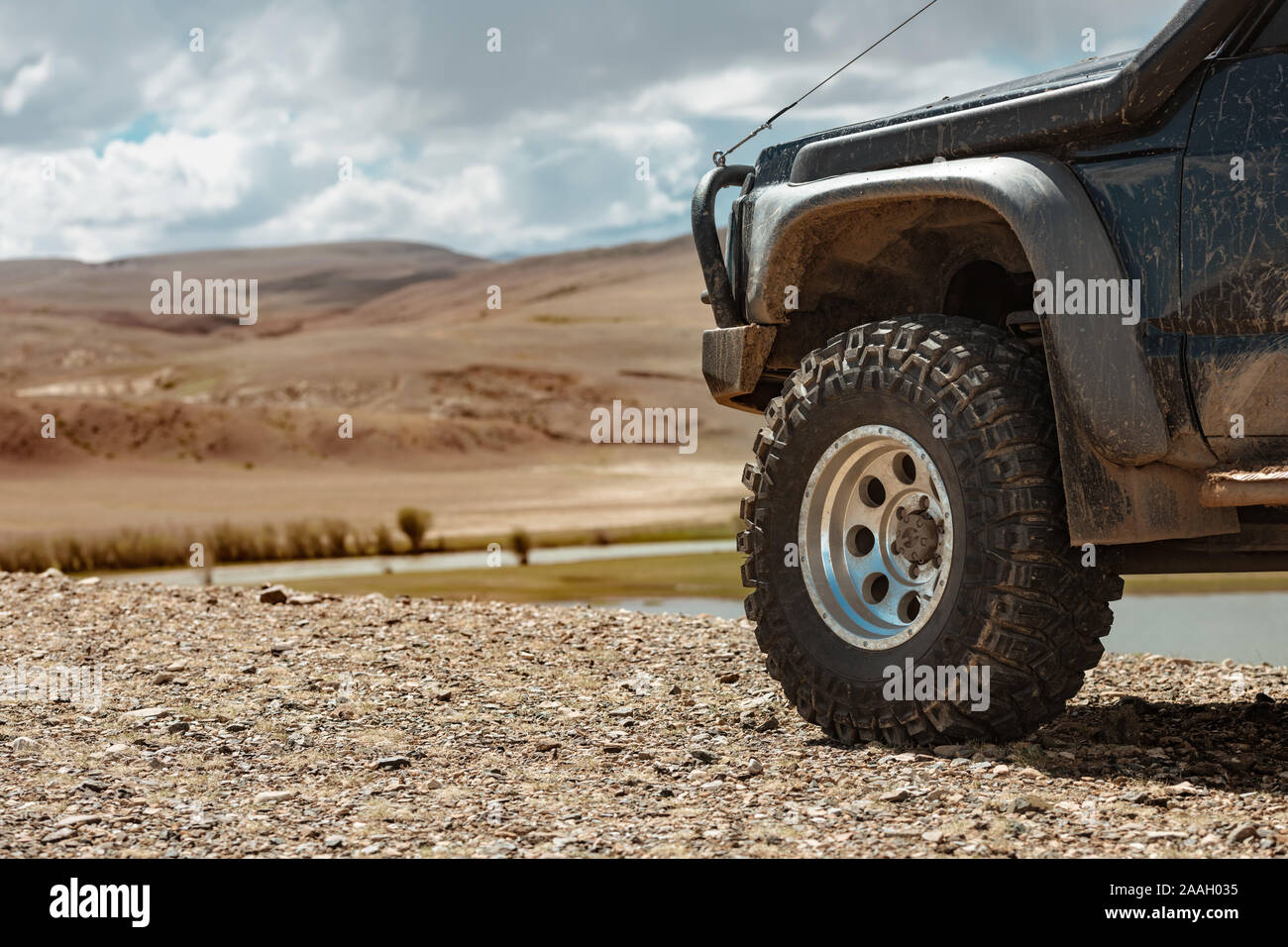 Aggressive off road ready car in mountains. Closeup photo of mud terrain wheel Stock Photo