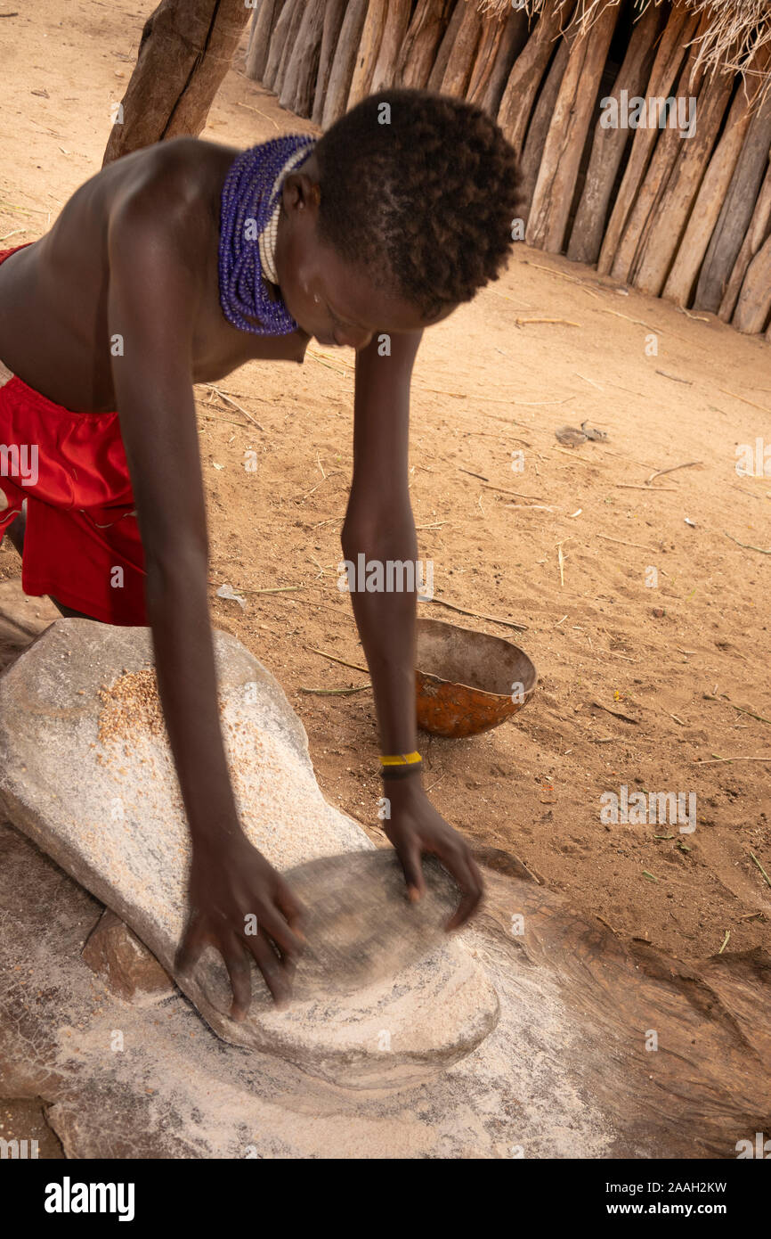 Ethiopia, South Omo, Kolcho village, young girl grinding grain on stone to make flour Stock Photo
