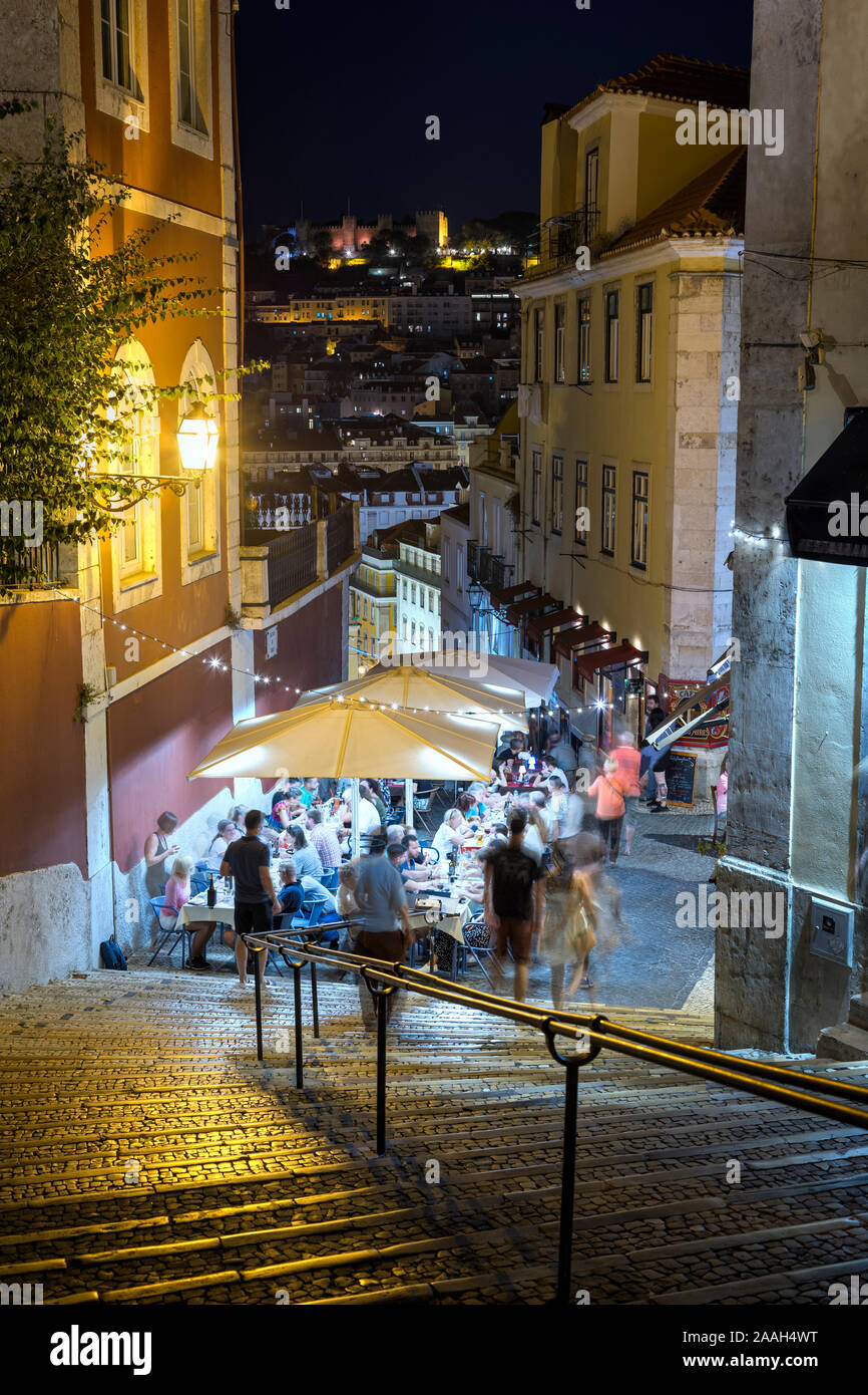 People dining al fresco at Calcada do Duque, cobblestoned pedestrian street that connects Bairro Alto and Rossio in Lisbon, Portugal, in the evening. Stock Photo