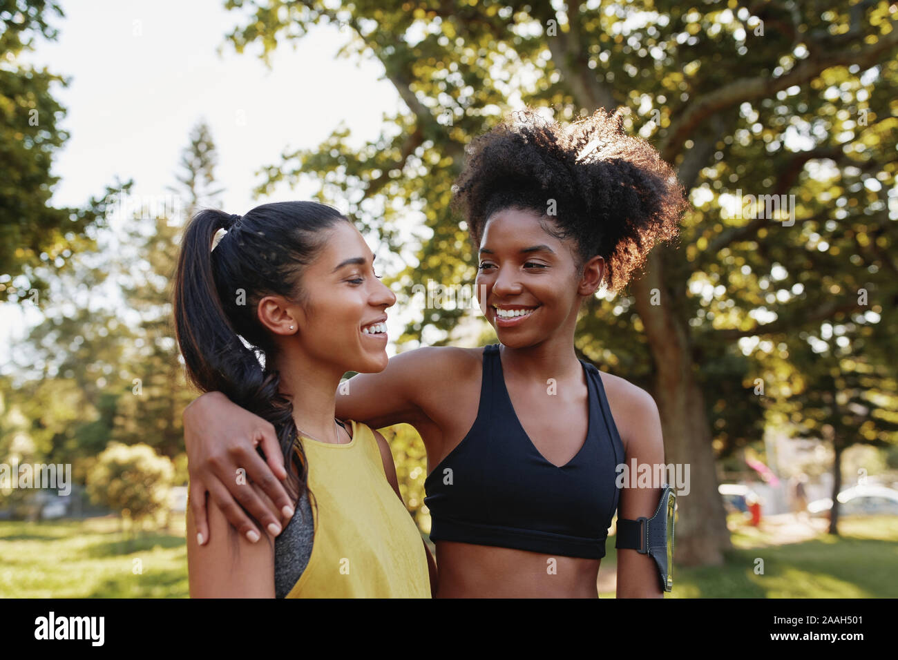 Cheerful young sporty multiethnic female friends hugging eachother and ...