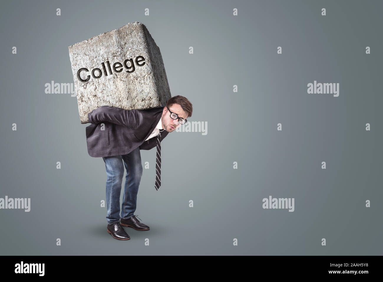 Man carrying a heavy stone marked with College Stock Photo