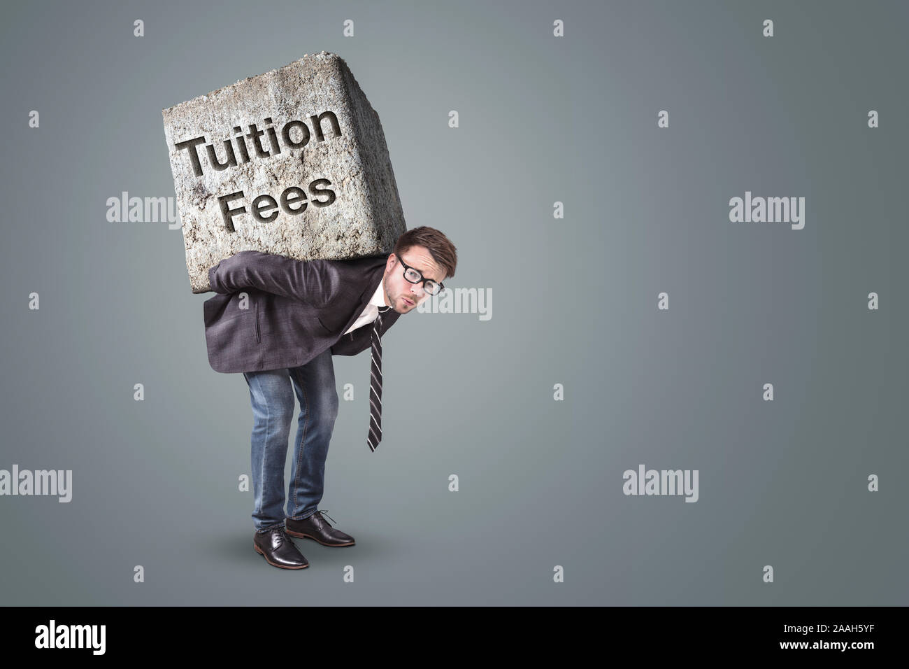 Man carrying a heavy stone marked with Tuition Fees Stock Photo - Alamy