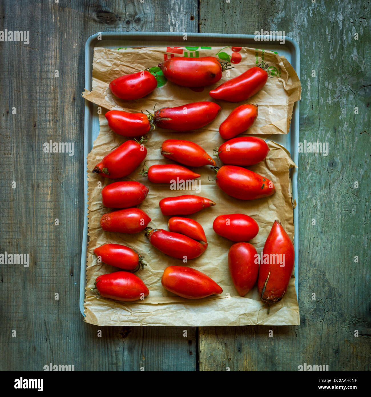 High angle view of grape tomatoes on a tray on the wooden table under the lights Stock Photo