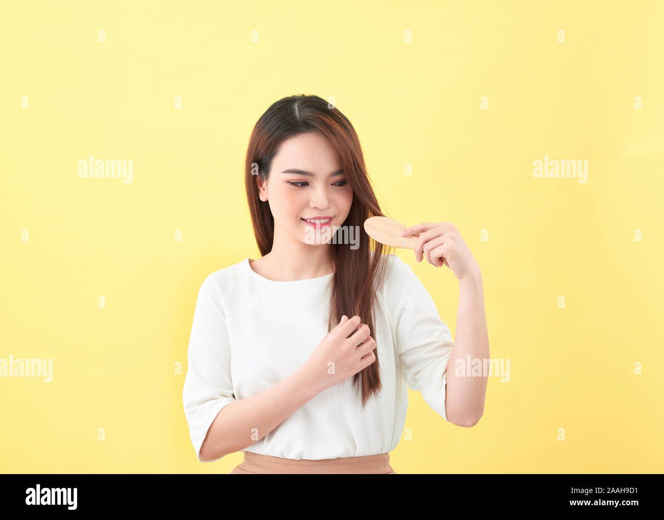 Portrait of beautiful young woman combing her hair and smiling Stock Photo