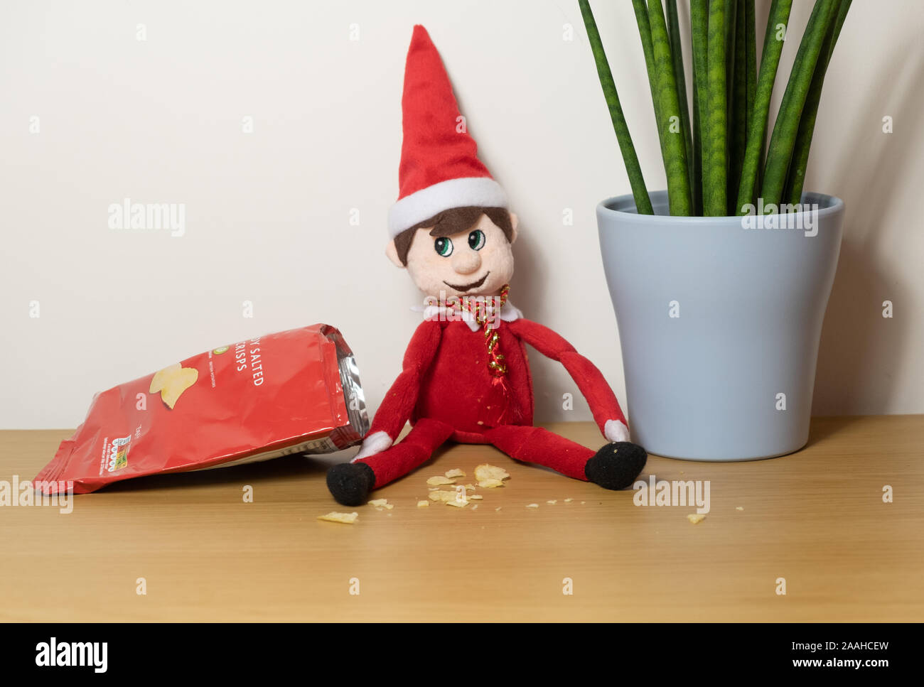 Christmas elf behaving badly, eating all the snacks and crisps. Stock Photo