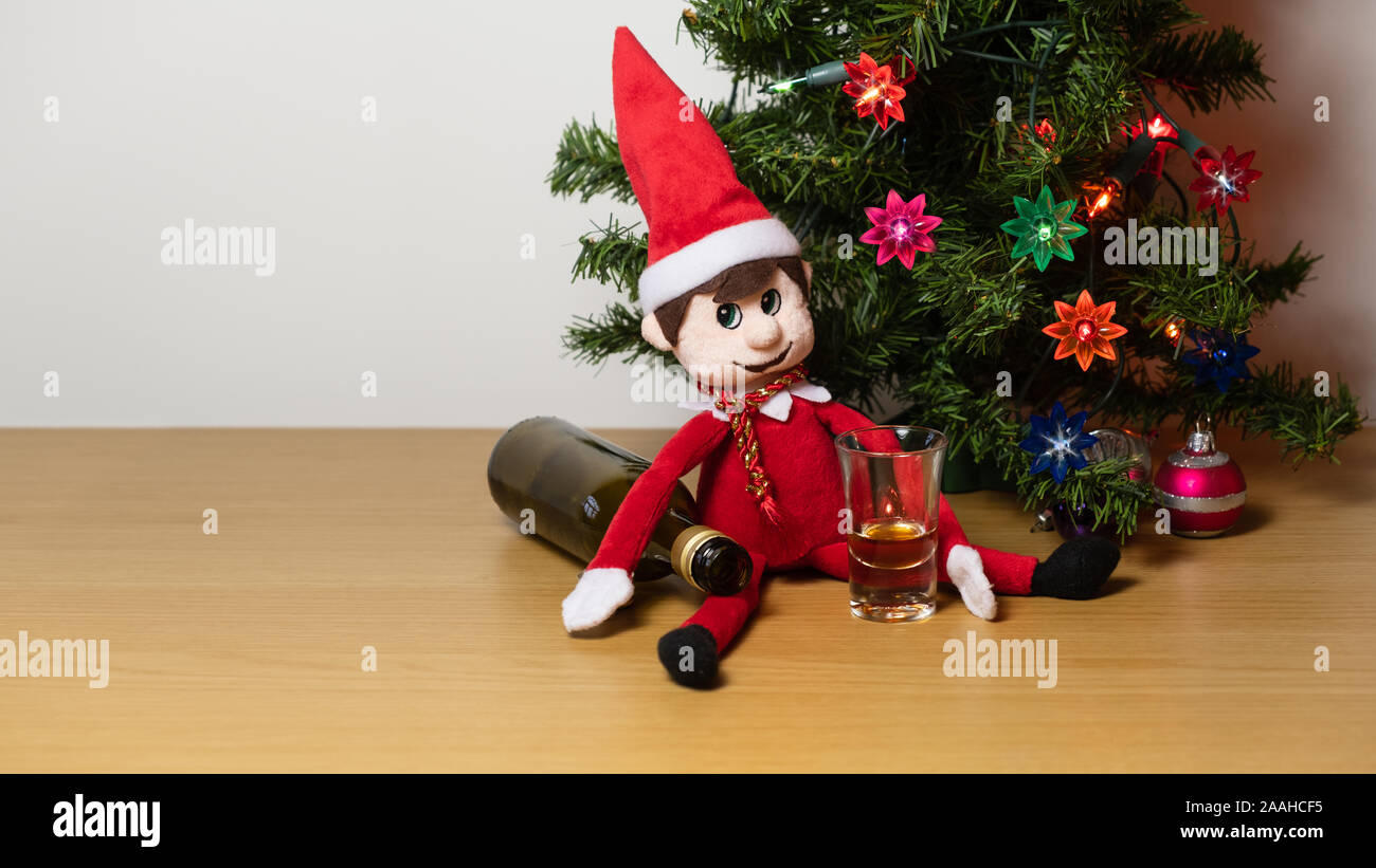 Christmas elf being naughty drinking wine or alcohol. Cute tradition of sending Santa's elf to check up on children just before christmas. Stock Photo
