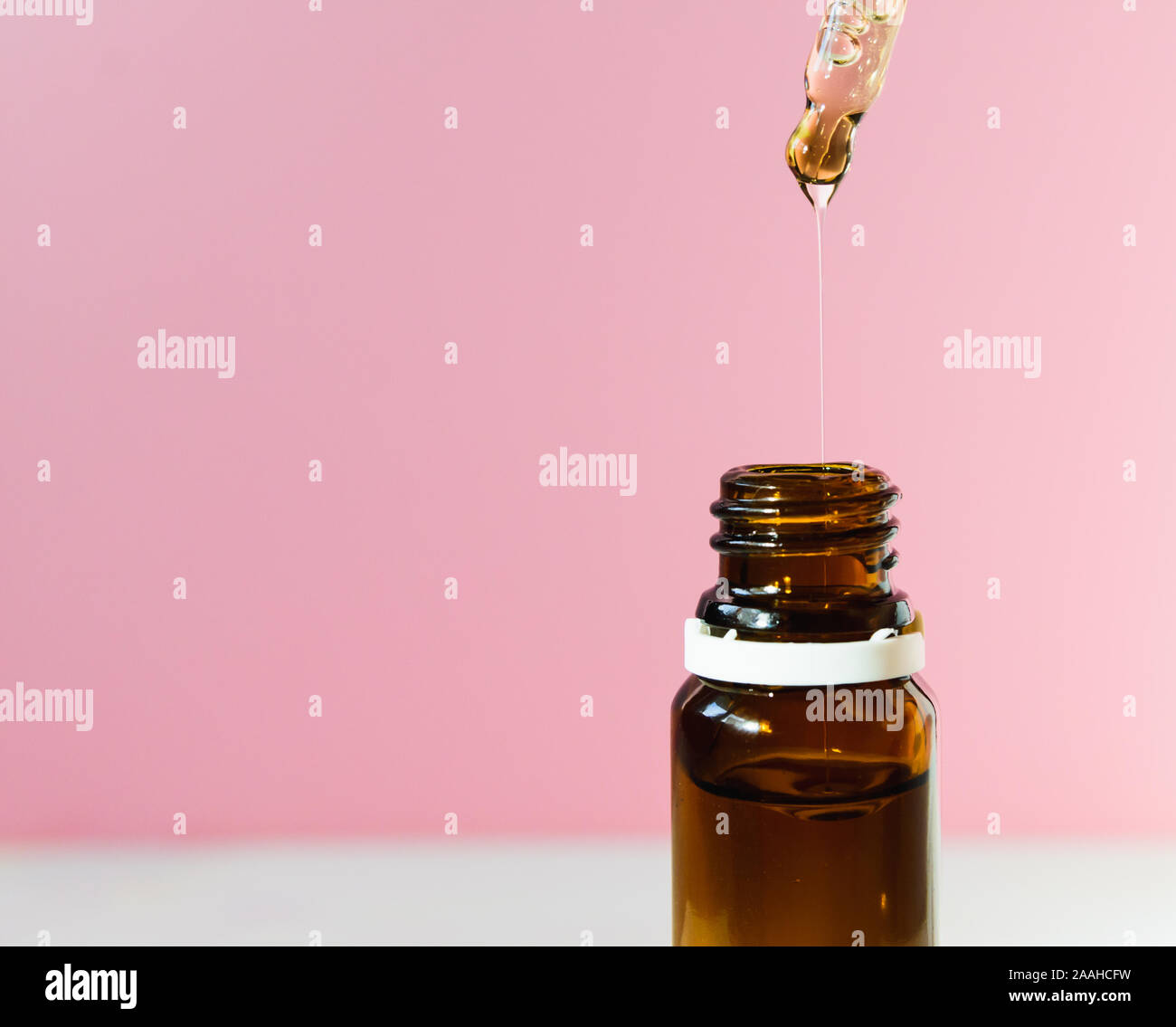 cosmetic product, bottle with hyaluronic acid on a pink background, close-up. Copy space. Stock Photo