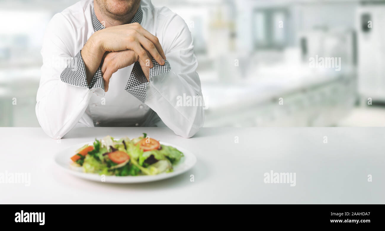 chef in restaurant kitchen with fresh salad plate. copy space Stock Photo