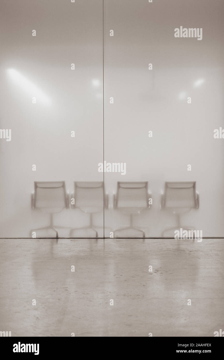Empty chairs behind a glass office wall partition - waiting room - empty office space - minimal glass office with seating - empty seats background Stock Photo