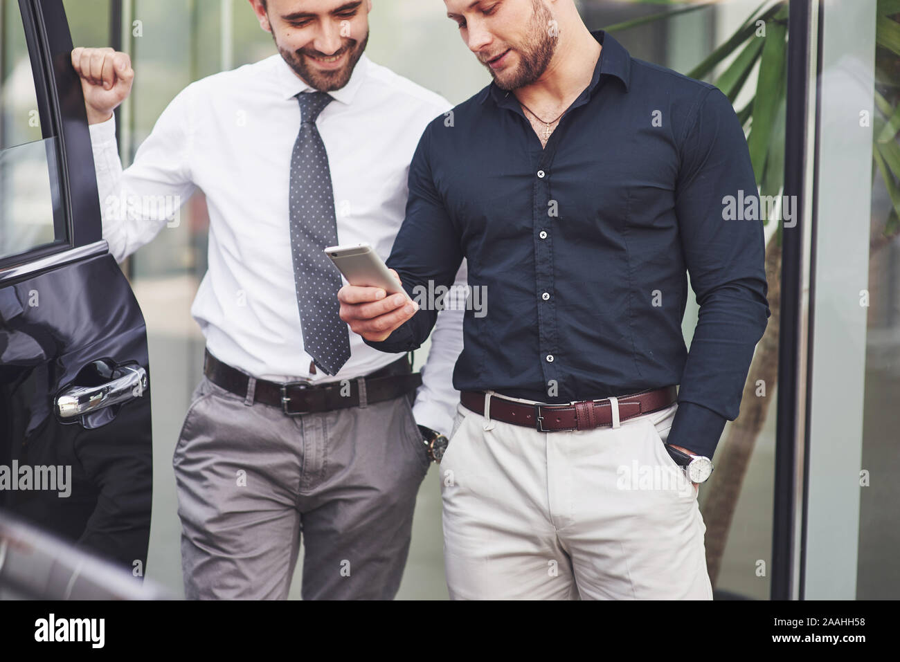 Two happy, confident young businessmen standing by the office Stock Photo