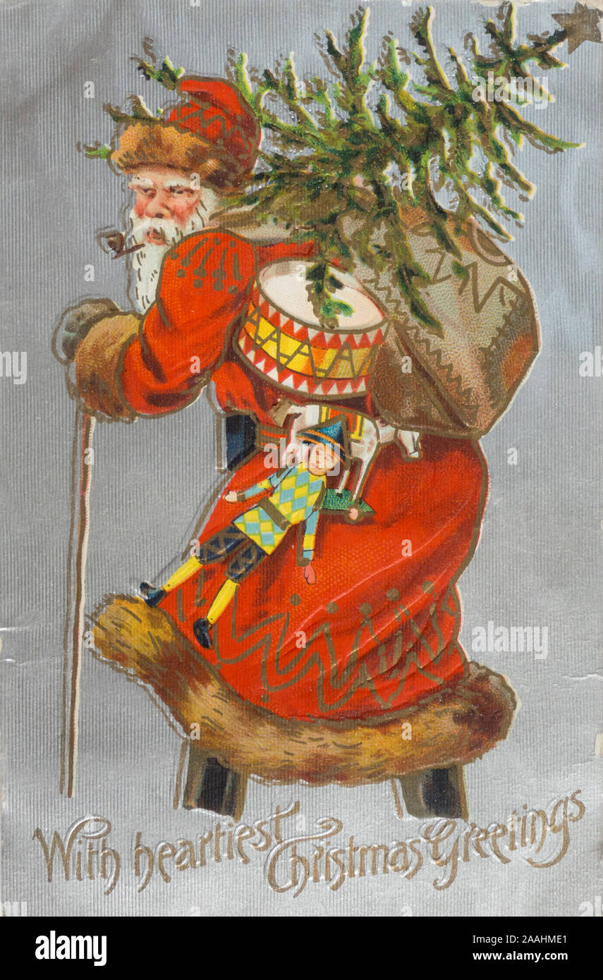 An old Santa on his way with presents in a sack and Christmas tree on his back, smoking a pipe, colorful with a silver background, Vintage Christmas post card mailed ca 1910 in New York USA Stock Photo