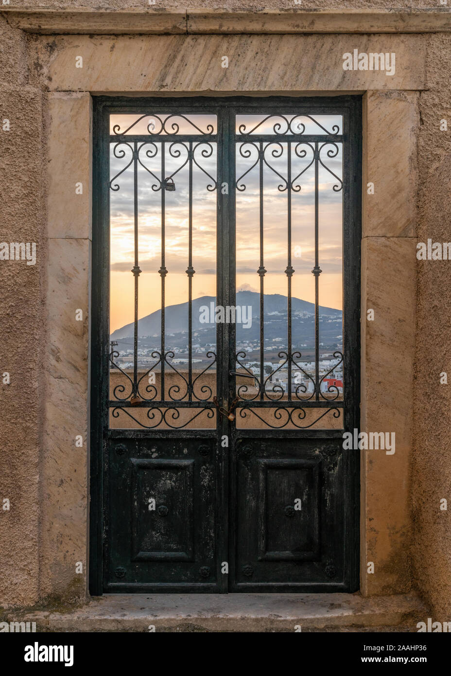 Black old metal double doors with sunrise sky and mountain in the background. Stock Photo