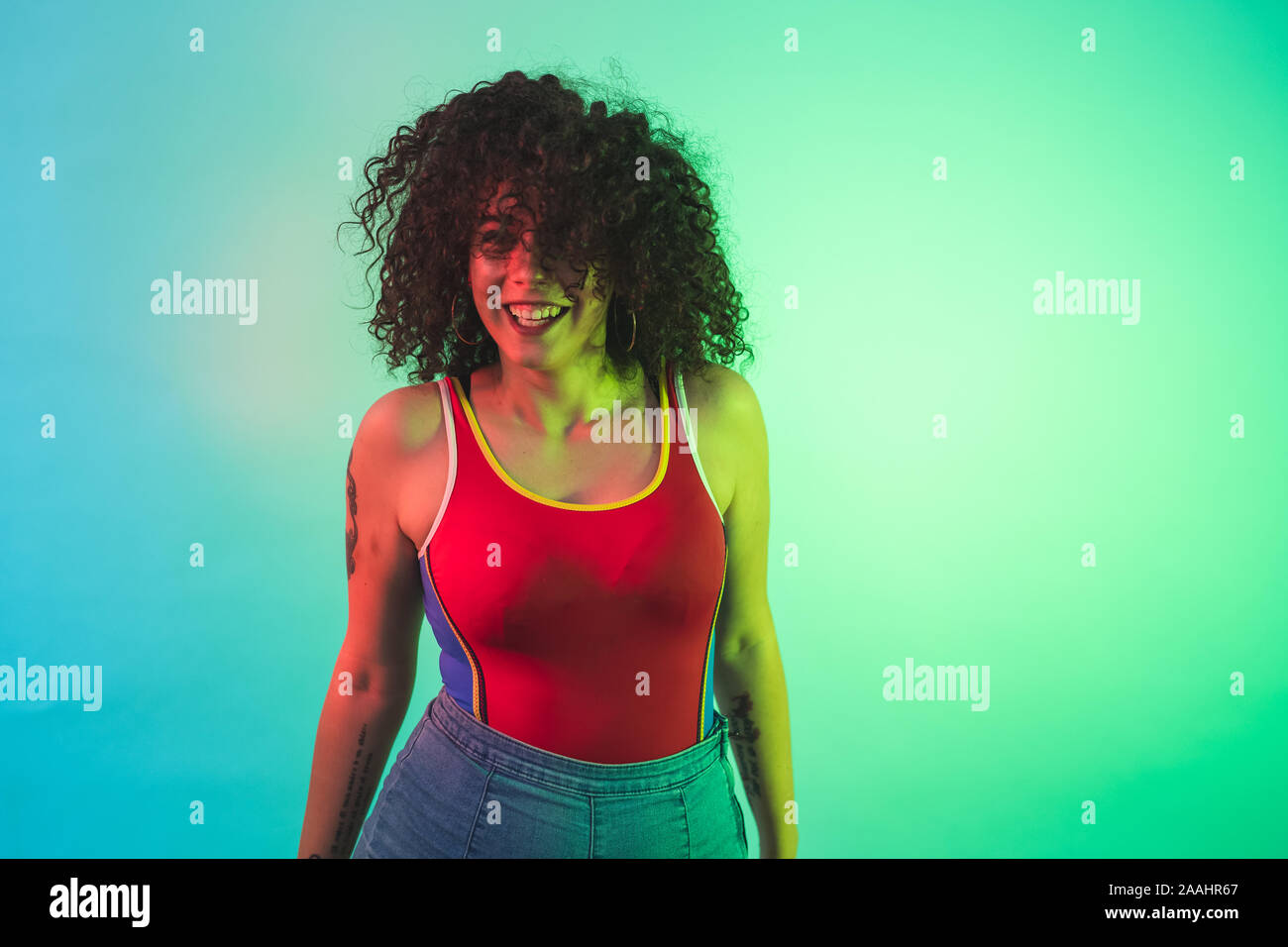 Young woman in red tank top posing against turquoise background Stock Photo