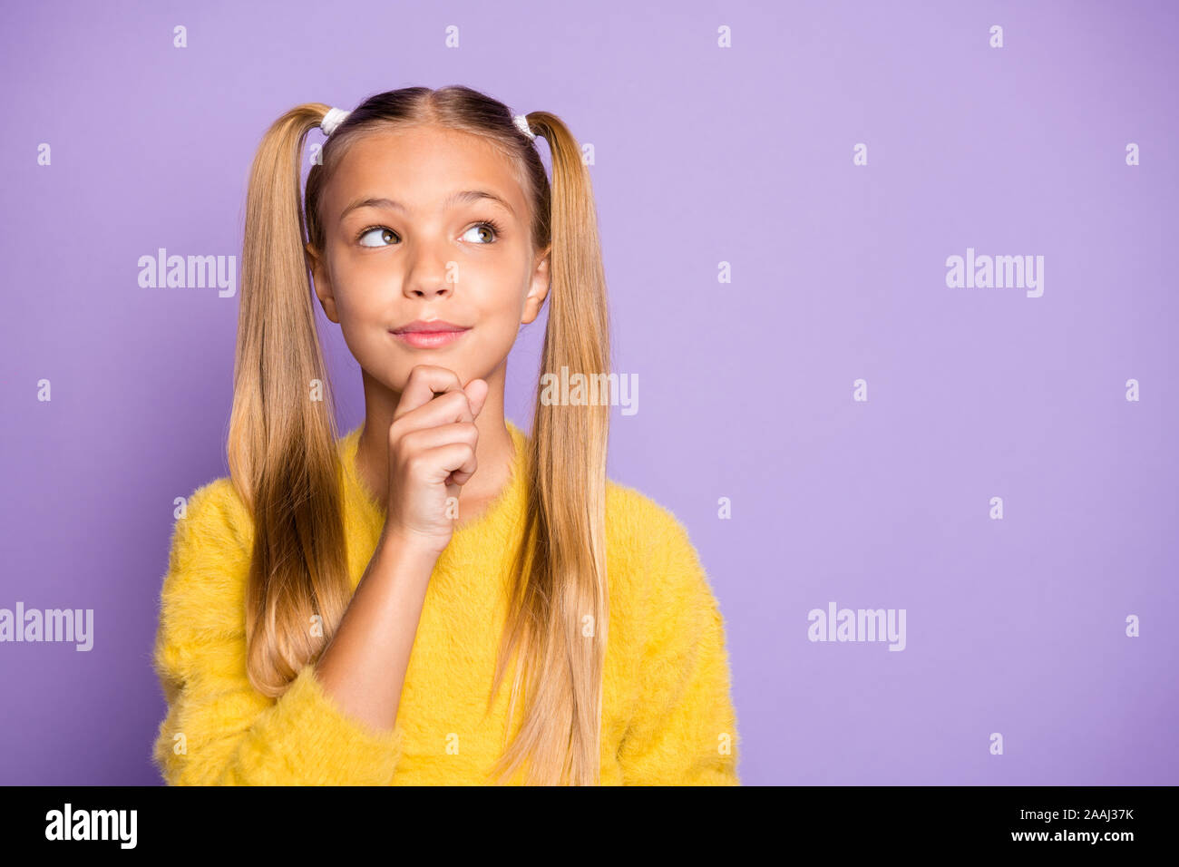 Photo of pensive casual girl touching her chin wearing yellow sweater looking into empty space isolated over pastel violet color background Stock Photo