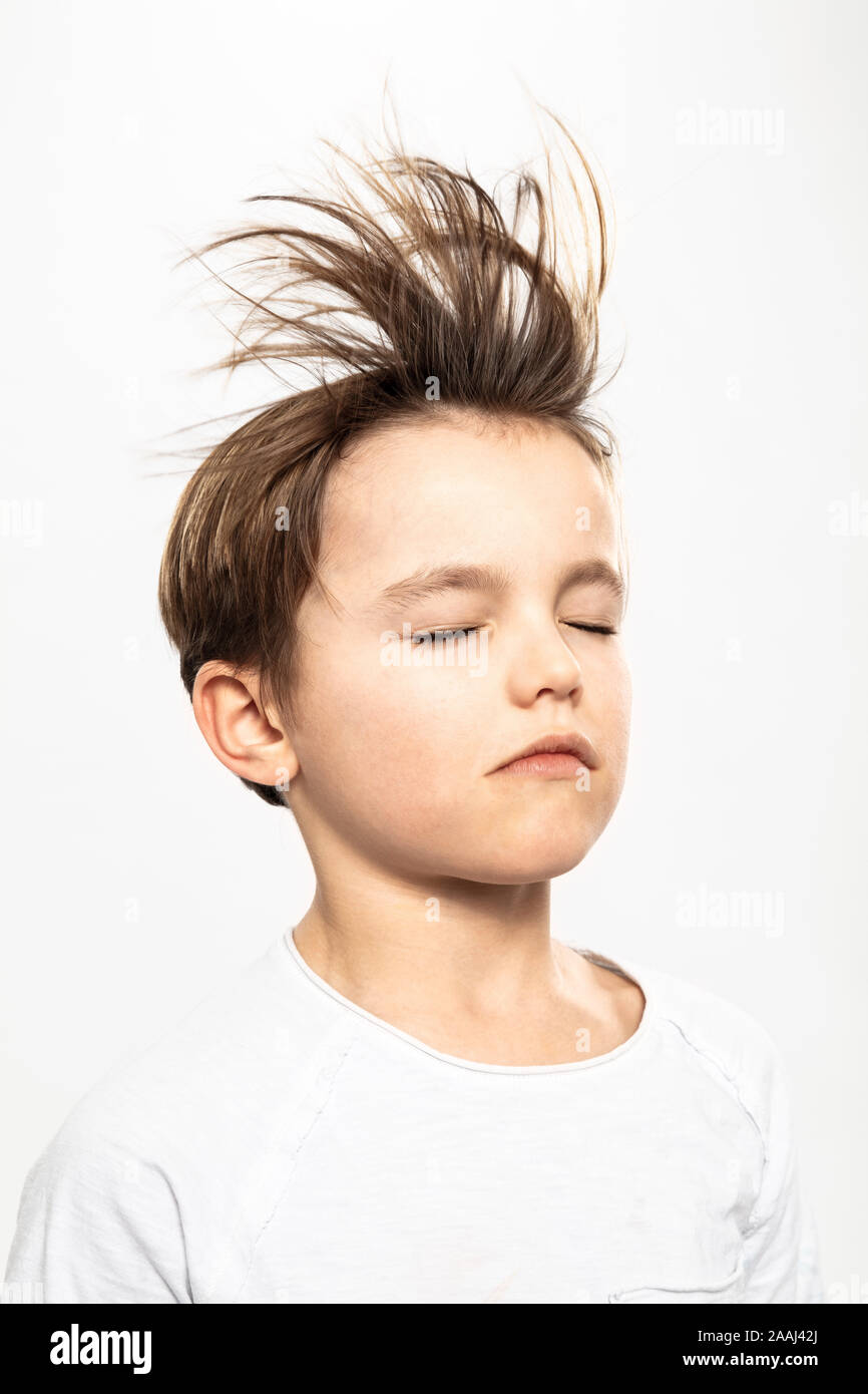 Boy with flying hair closing eyes, white background Stock Photo