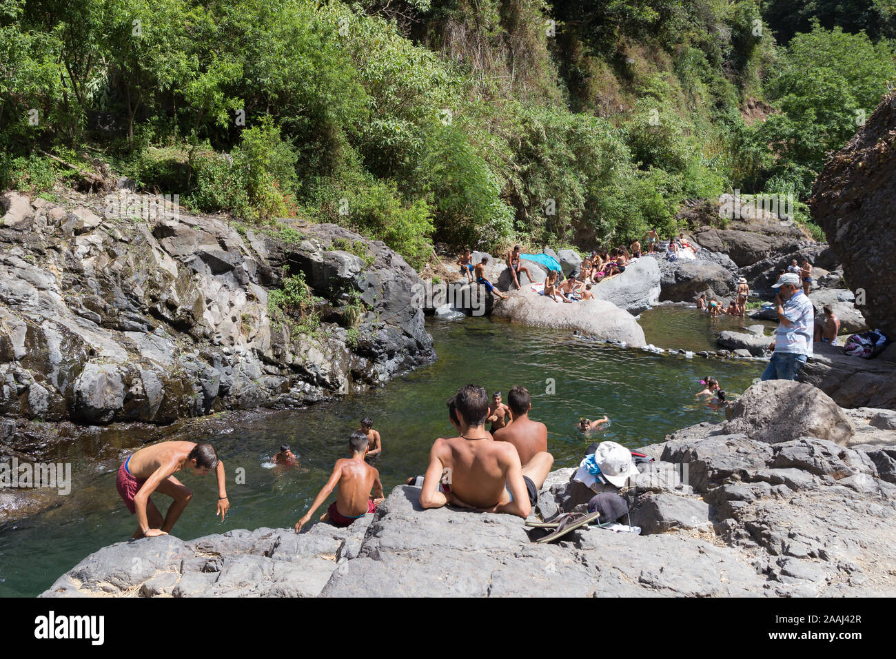 CURRAL DAS FREIRAS, MADEIRA, PORTUGAL - AUGUST 2019: Overview of local people bathing in 'Poco dos Chefes' natural rocky beach in Curral das Freiras, Stock Photo