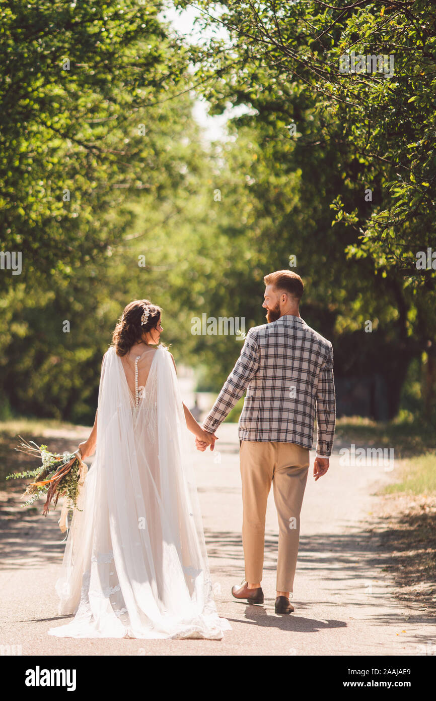Happy bride and groom holding hands and walking in garden wedding day ...