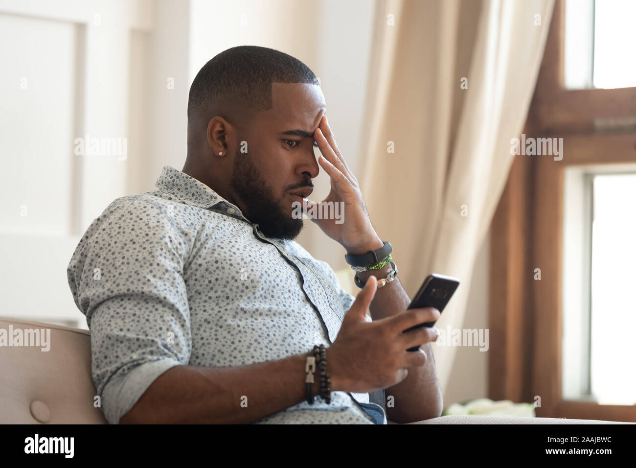 Frustrated african American man disappointed by bad message Stock Photo