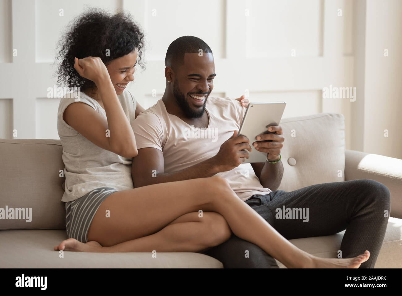 Overjoyed biracial couple feel excited reading news on tablet Stock Photo