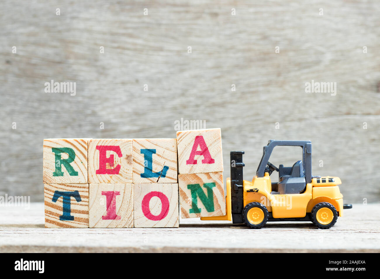 Toy forklift hold letter block a, n to complete word relation on wood background Stock Photo