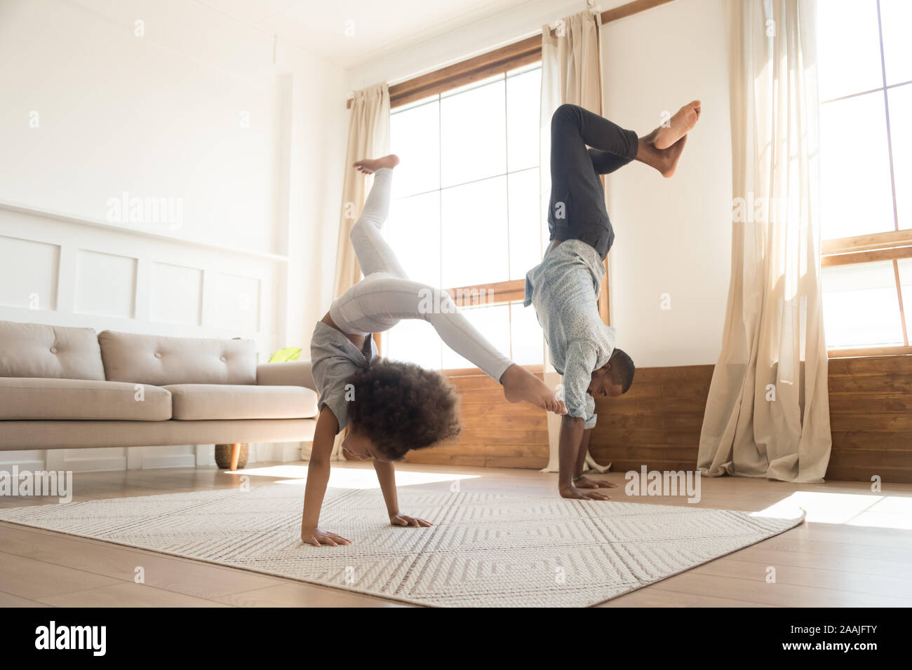 Active biracial dad and daughter exercise at home together Stock Photo