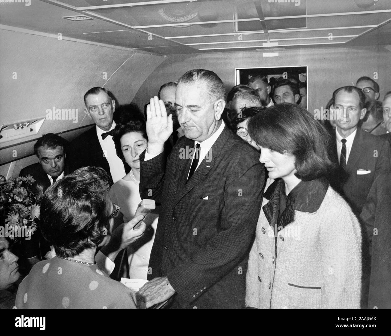 Lyndon B. Johnson, 36th President of the USA, taking the oath of office aboard Air Force One at Love Field Airport hours after the assassination of John F. Kennedy . Former first lady Jackie Kennedy is to his left and his wife, Lady Bird Johnson to his right. The swearing-in was conducted by Judge Sarah T. Hughes. Stock Photo