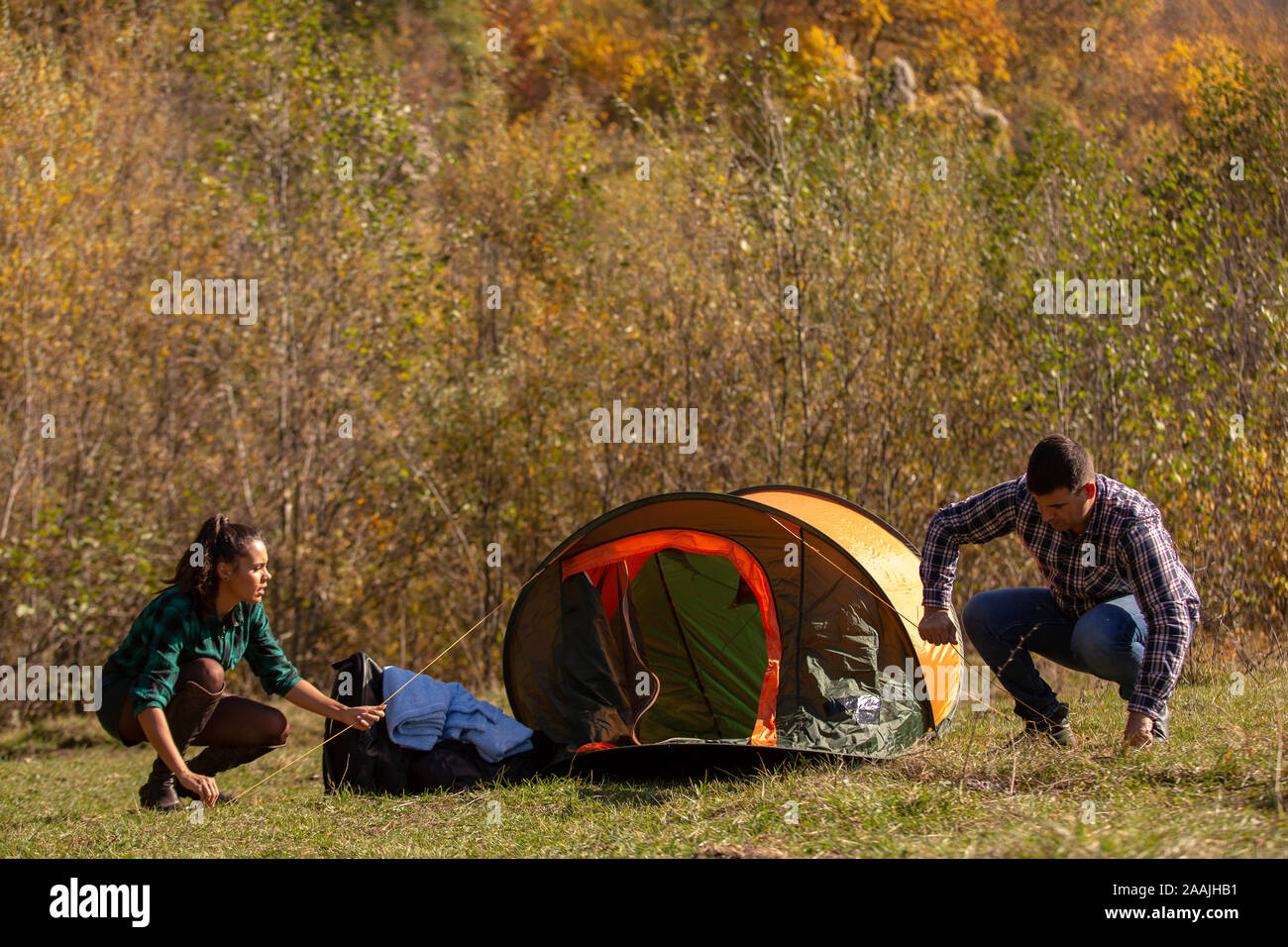 Young couple installing tent on mountain. Relax vacation Stock Photo